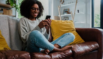 Woman sitting on couch looking at phone