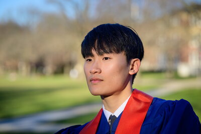 student in graduation gown gazes into distance