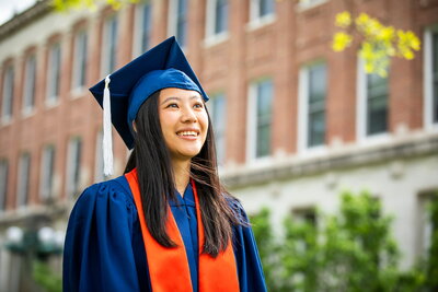 student in graduation cap and gown gazes into distance